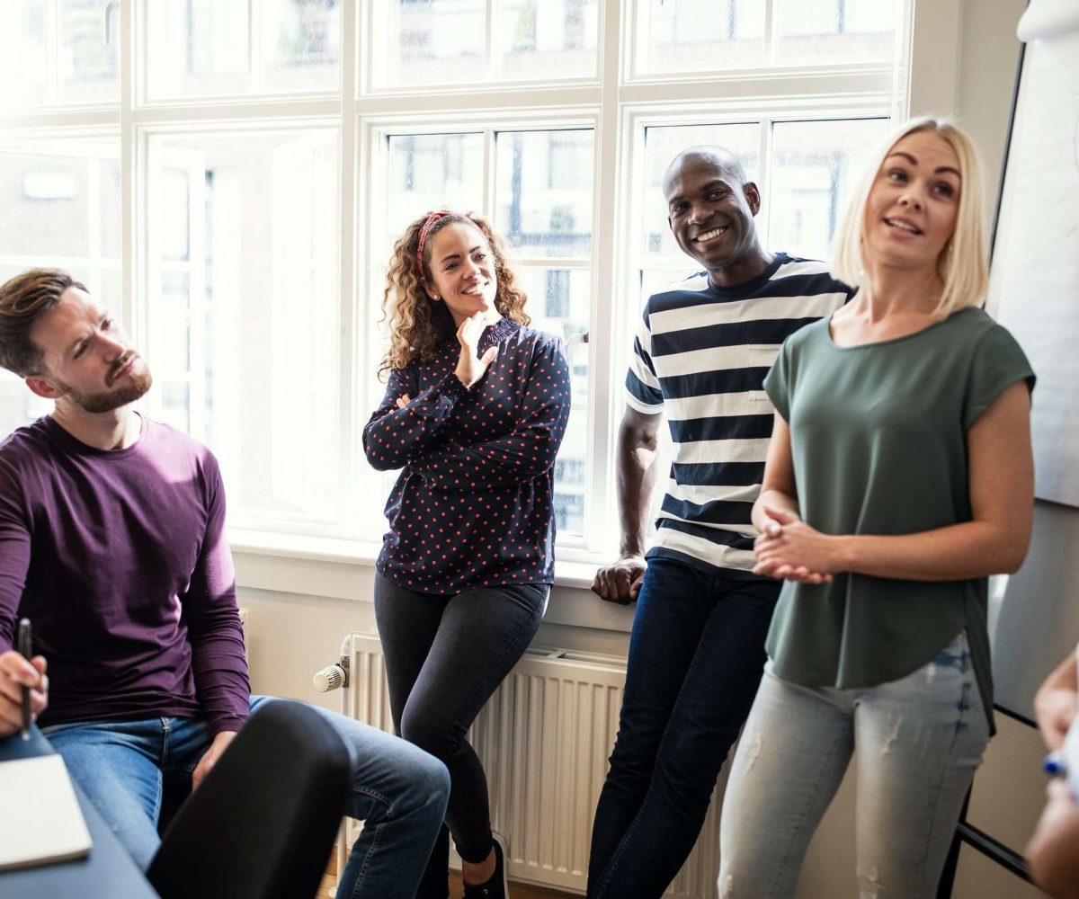 Smiling coworkers talking together after an office presentation